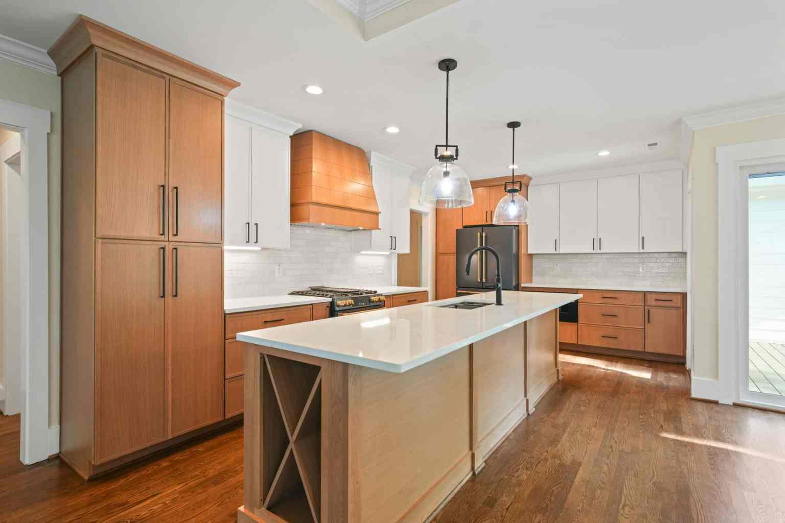 Kitchen remodel with white oak cabinetry, a wood range hood and a quartz island