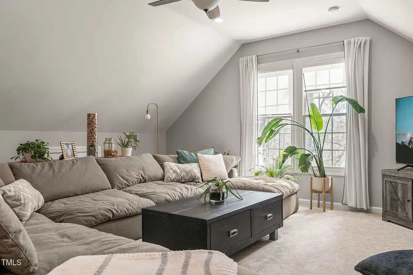 Finished attic living space with sloped ceilings, a sectional sofa and a dormer window