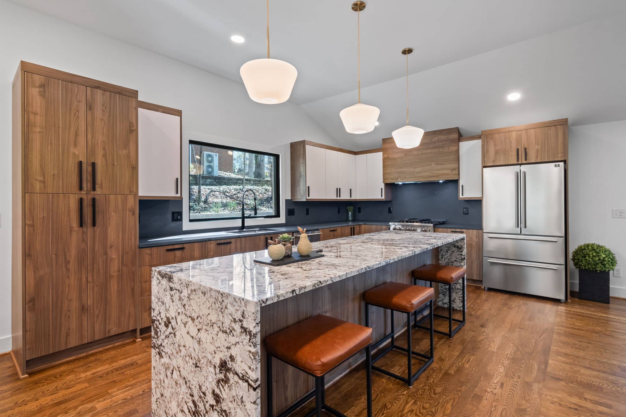 Remodeled kitchen with walnut cabinetry, a granite island and brass pendant lights