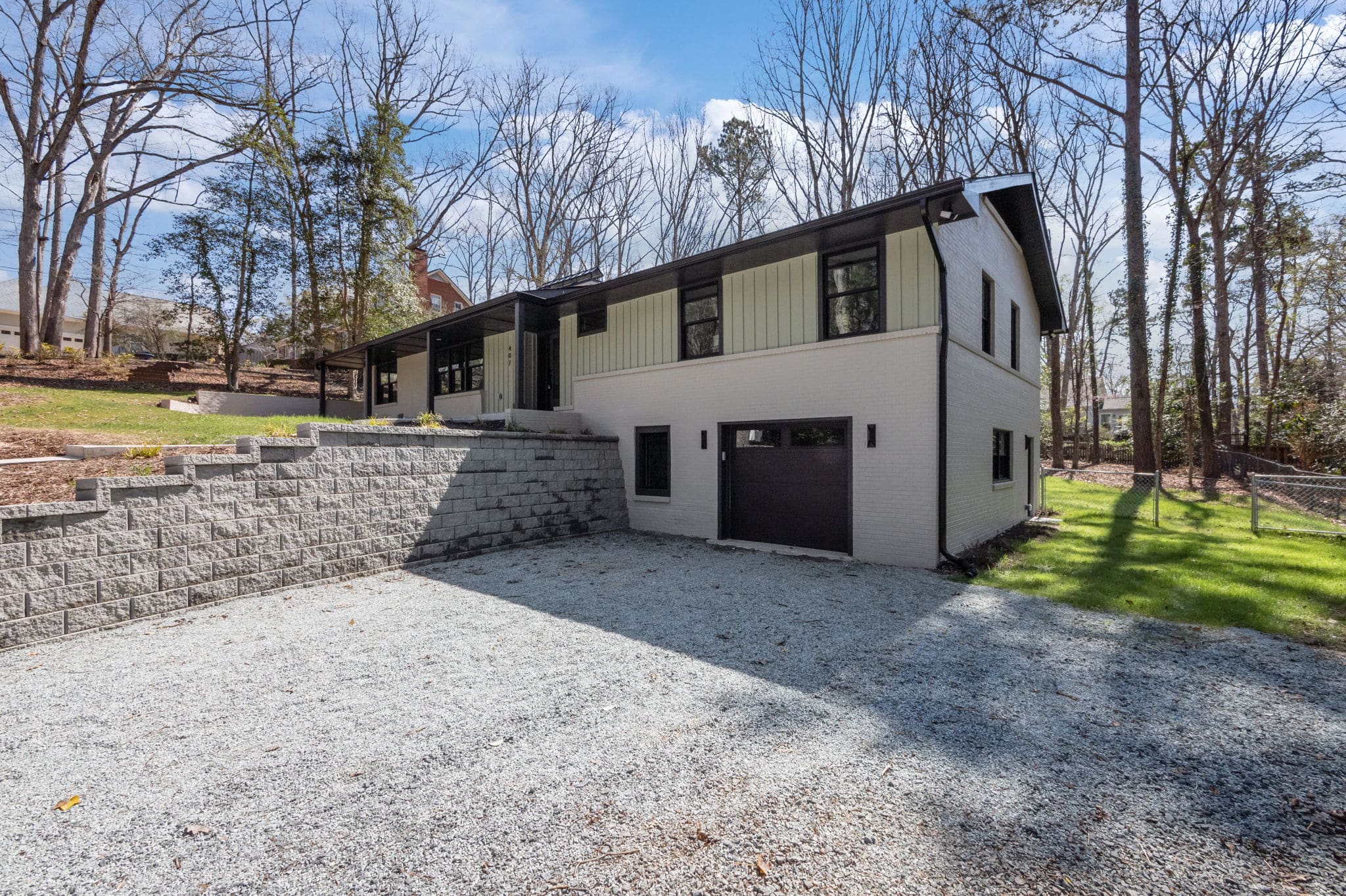 Renovated mid-century home with painted brick, board-and-batten siding and black-framed windows