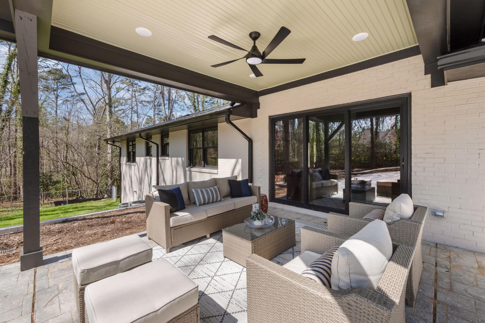 Covered outdoor living area with stone paving, a beadboard ceiling and sliding doors into the house